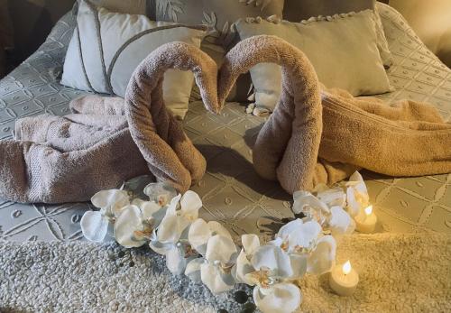 dos toallas y flores en una cama con velas en Suite romantique avec sauna et jacuzzi, 