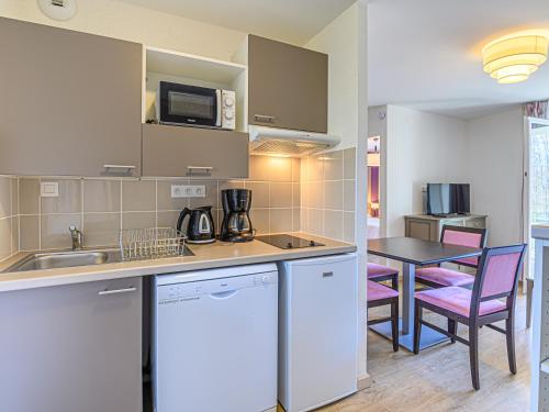 a kitchen with a sink and a table with chairs at Vacancéole - Les Rives de Pont-Aven in Pont-Aven