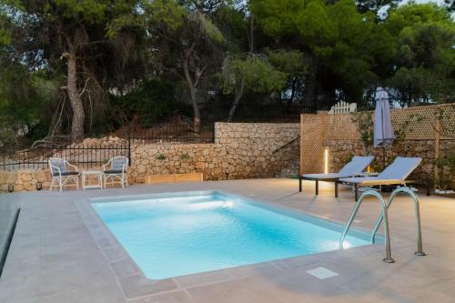 uma piscina com cadeiras e uma mesa ao lado de uma parede em Iliana Exclusive Villa - Private Pool - Walking Distance To Beach em Porto Heli
