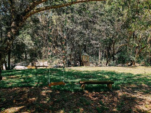 a park with a swing and a bench in the grass at Suíte com cachoeira no quintal in Antônio Carlos
