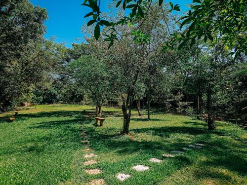 a park with a bench and trees in the grass at Suíte com cachoeira no quintal in Antônio Carlos