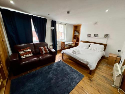 a bedroom with a bed and a leather couch at Stay in Bloomsbury1 in London