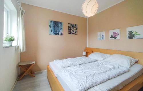 um quarto com uma cama com lençóis brancos e fotografias na parede em Awesome Home In Vlagtwedde With Indoor Swimming Pool em Vlagtwedde