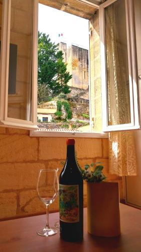 a wine bottle and a glass on a table with a window at Hôtes de Saint Emilion in Saint-Émilion
