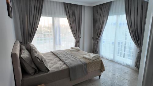 a bedroom with a bed and large windows at White Bay Resort in Didim