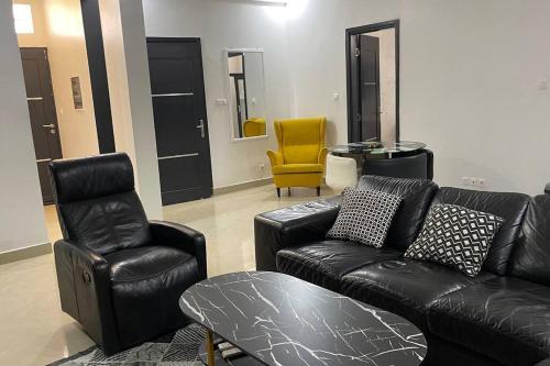 a living room with a leather couch and two chairs at Appartement Haut Standing in Dakar
