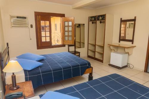 a bedroom with two beds and a table and a desk at Hotel Colonial in São Lourenço