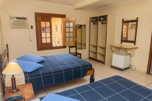 a bedroom with two beds and a table and a desk at Hotel Colonial in São Lourenço