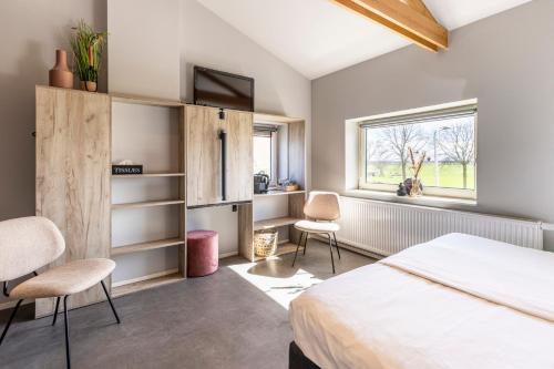 a bedroom with a bed and two chairs and a window at Weeruusz in Kolderwolde