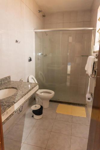a bathroom with a shower and a toilet and a sink at Hotel Colonial in São Lourenço
