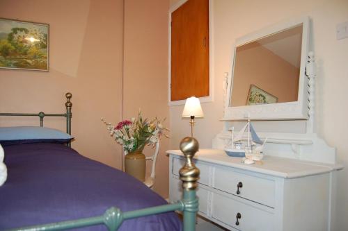 Un dormitorio con una cama y una cómoda con espejo. en Seagull Beach House, en Tywyn