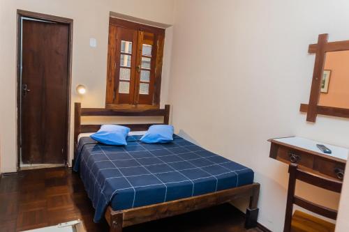 a bedroom with a bed with blue pillows on it at Hotel Colonial in São Lourenço