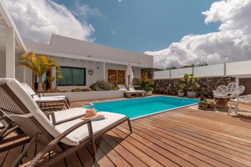 een achtertuin met een zwembad en een houten terras bij Villa Shepherd Lajares - LUXURY VILLA FUERTEVENTURA in Lajares