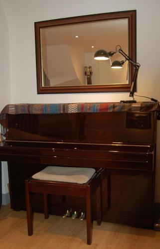 a brown piano with a lamp and a mirror at Ty Del - Beautiful Home in Tywyn in Tywyn