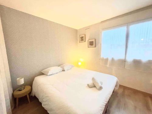 um quarto com uma grande cama branca e uma janela em Le bellevue (parking gratuit) em Besançon