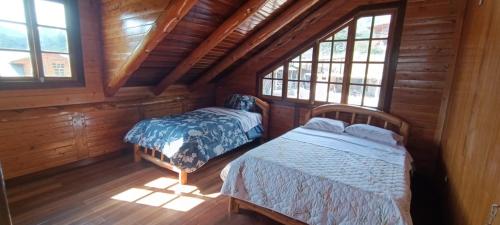 um quarto com 2 camas num chalé de madeira em CABAÑAS RANCH OXAPAMPA em Oxapampa