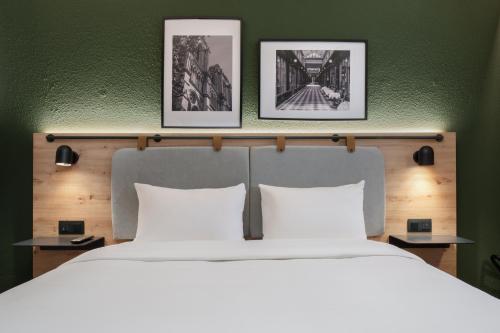 1 dormitorio con 1 cama grande y 3 cuadros en la pared en Campanile Lille Est - Villeneuve D'ascq, en Villeneuve d'Ascq