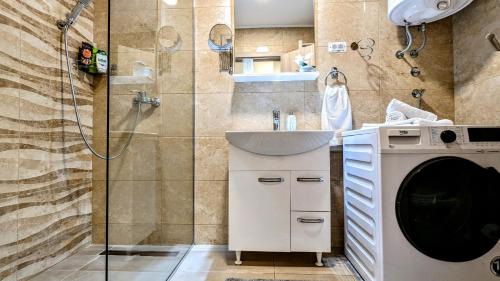 La salle de bains est pourvue d'une douche, d'un lavabo et d'un lave-linge. dans l'établissement Blue Lagoon in city center - apartmani-nsmilos, à Novi Sad