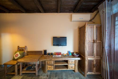 Habitación con mesa de madera y TV en la pared. en Yangshuo Tea Cozy, en Yangshuo