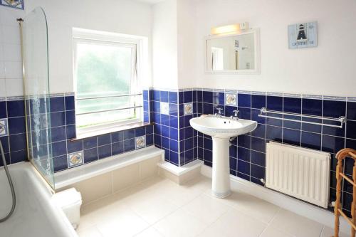 索爾瓦的住宿－Tremaes Solva，蓝色瓷砖浴室设有水槽和窗户
