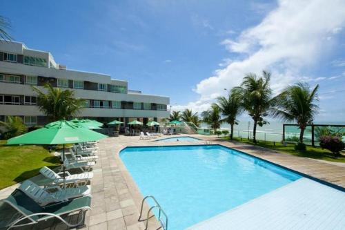 een zwembad met stoelen en een parasol en een gebouw bij Sonia Flats Natal - No Apart Hotel Ponta Negra Beach in Natal