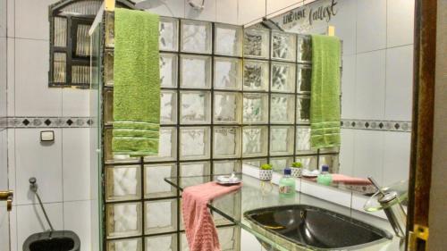 a bathroom with a sink and a shower with green towels at Suíte Green in Praia Grande