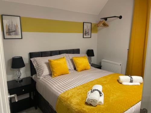 a bedroom with a bed with yellow pillows and towels at 2 Bedroom House & Parking 2 washrooms in Reading