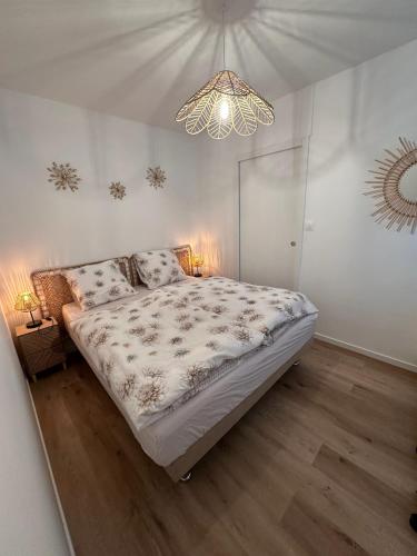 une chambre avec un grand lit et un lustre dans l'établissement Appartement Marina Deauville Marinaland, à Deauville