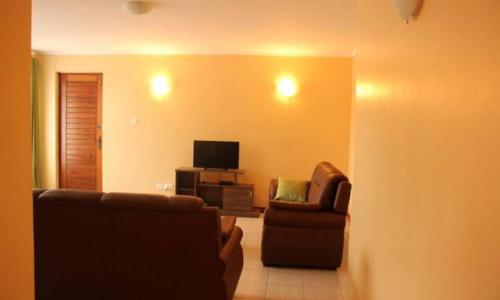 a living room with two chairs and a television at LIA Hotel & Training Centre in Nairobi