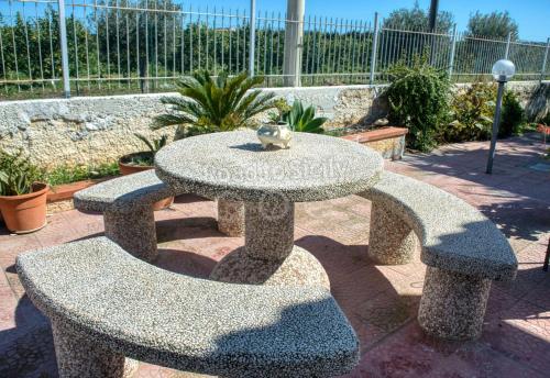 a stone table and two benches with a bird sitting on top at Aleari Villa Fanusa in Fanusa