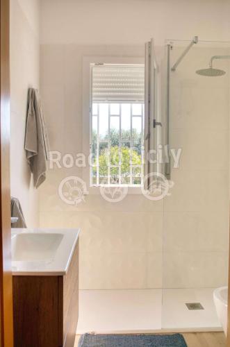 a bathroom with a shower and a sink and a window at Aleari Villa Fanusa in Fanusa
