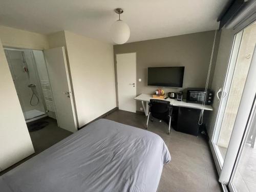 une chambre avec un lit et un bureau avec une télévision dans l'établissement Séjournez chez Cédric et Julie, à Montesson