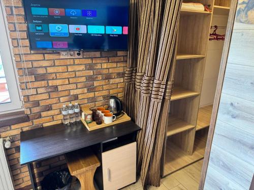 a room with a table and a tv on a brick wall at Готель Довбуш in Yaremche