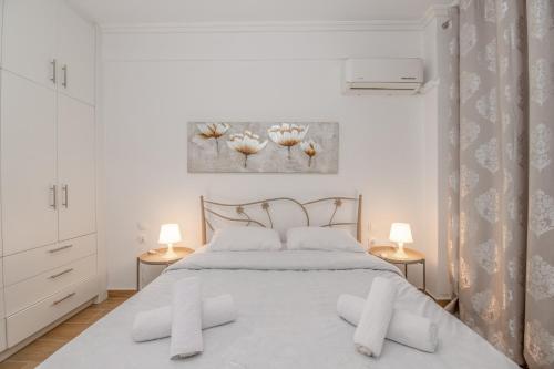 a white bedroom with a bed with two lamps at Kallithea Gardenspot in Athens