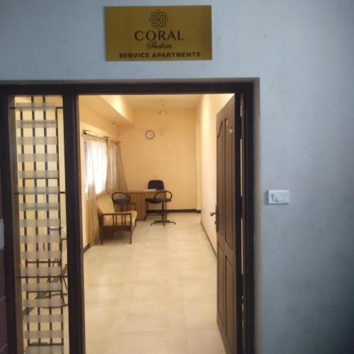 einen Flur, der in ein Zimmer mit einem Tisch und Stühlen führt in der Unterkunft Coral Shelters Keelavasal in Madurai