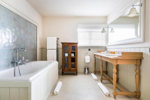 a bathroom with a tub and a table and a sink at Les Clefs de Troplong Mondot in Saint-Émilion