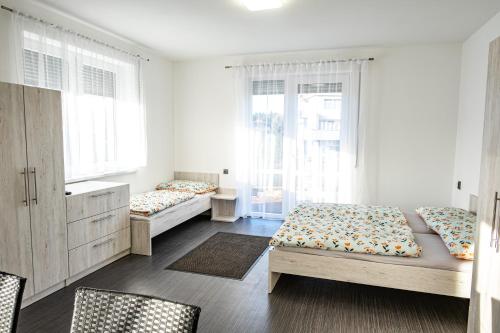 a bedroom with two beds and two windows at Penzion Fann in Humpolec