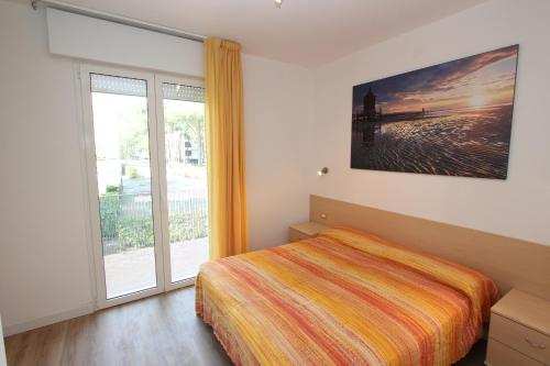 ein Schlafzimmer mit einem Bett und einem großen Fenster in der Unterkunft Tamerici in Bibione