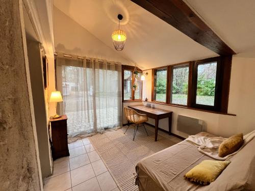 a bedroom with a bed and a desk and windows at Le Clos de la Michaudiere in Cellettes