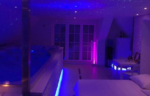 een woonkamer met paarse verlichting en een bad bij Aarts Wellness in As