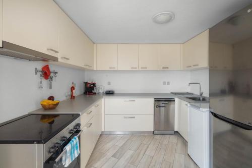 una cocina con armarios blancos y electrodomésticos de acero inoxidable en Villa Ganema 2, en Ganema