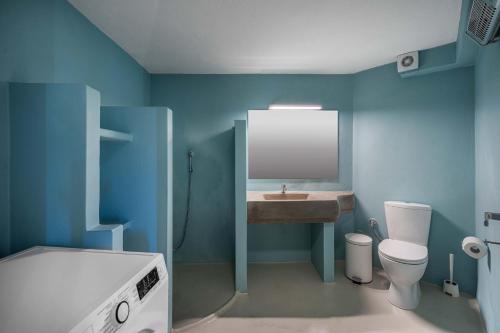 a blue bathroom with a sink and a toilet at Villa Ganema 1 in Ganema
