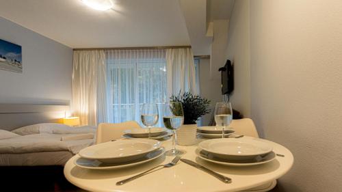 einen Esstisch mit Tellern und Weingläsern in der Unterkunft VacationClub - Livigno Apartament 28 in Heudorf