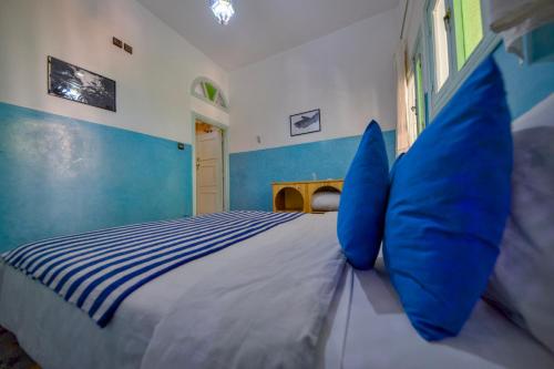 a blue and white bedroom with a bed with blue pillows at Maison d'hôtes Dar Farhana in Ouarzazate