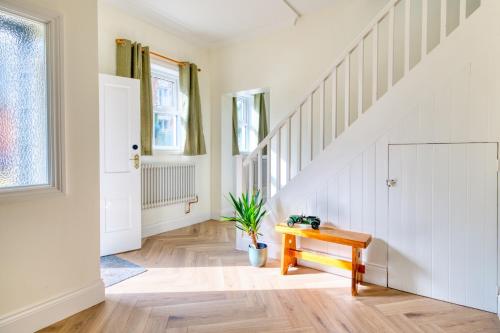 uma escadaria com um banco de madeira num quarto com paredes brancas em The Yorkshire Hosts - Enholmes Coach House em Hull