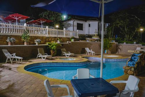 a swimming pool with chairs and an umbrella at night at Finca Villa Alicia in Barichara