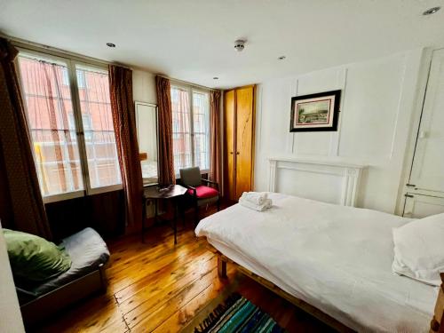a bedroom with a bed and a chair and windows at Stay in Bloomsbury2 in London