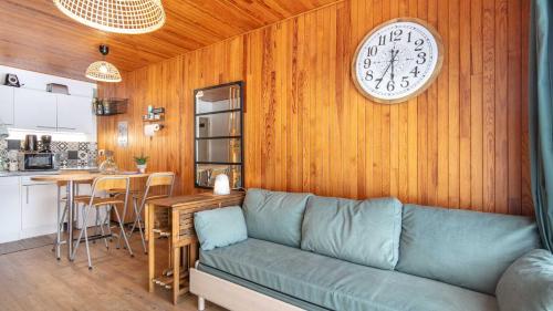 un salon avec un canapé et une horloge au mur dans l'établissement Le Carina -4- charmant Studio 4 pers, à Chamrousse