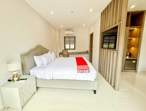 a bedroom with a white bed with a red blanket on it at Greenlife Village Phú Quốc in Phu Quoc