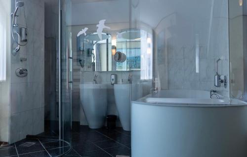 een badkamer met een douche, een bad en een wastafel bij Hotel De Torenhoeve in Burgh Haamstede